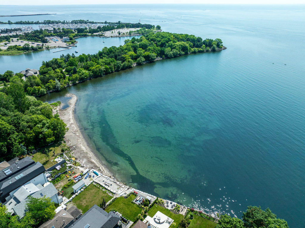 Aerial view of lakefront homes, a wooded peninsula, and a marina along Lake Ontario in Mississauga