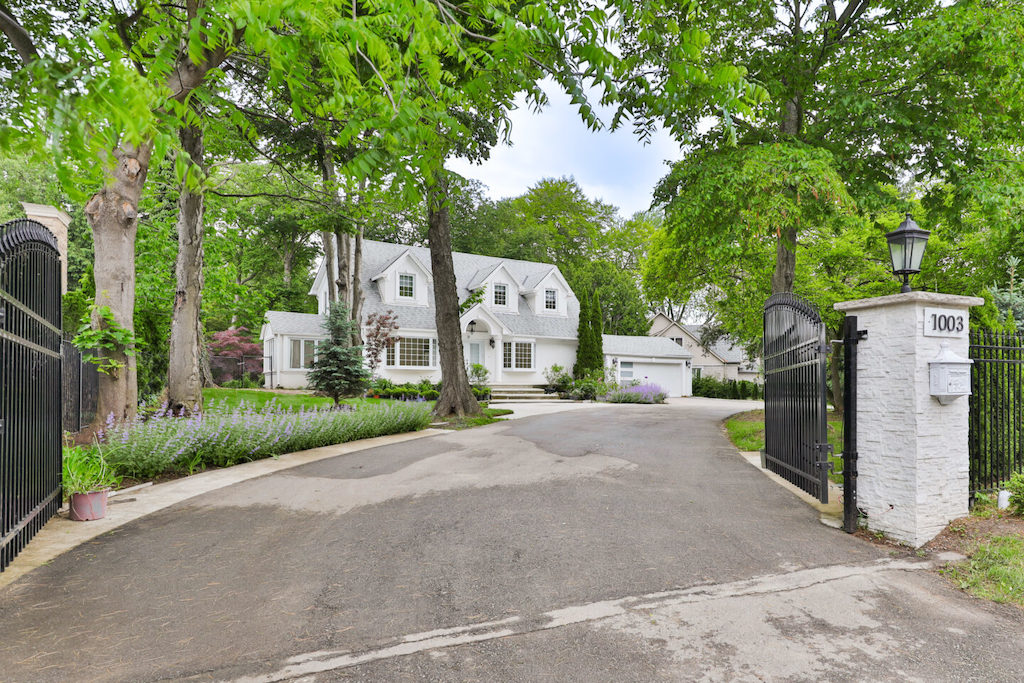Gated luxury estate with a long driveway and mature landscaping in Oakville